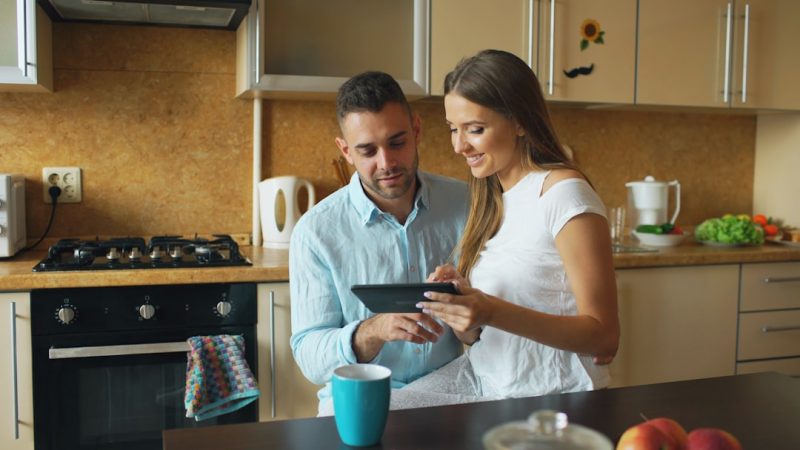 Parents planning the family budget on a laptop at the kitchen table